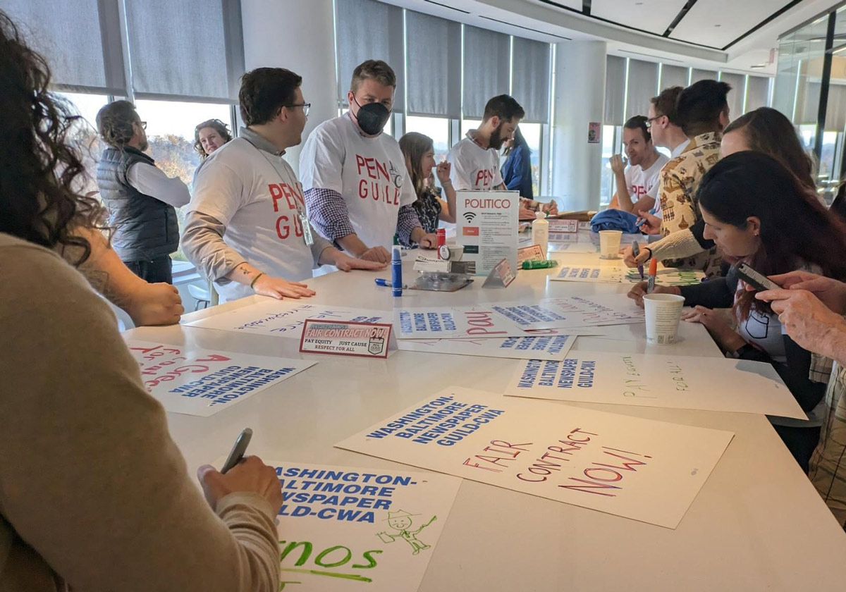 Workers at Politico and E&E News making posters demanding a first contract