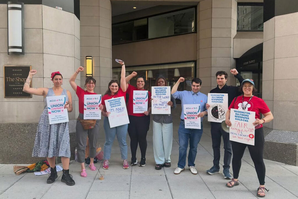 Workers of ACLU DC pose for a photo with signs supporting their union.