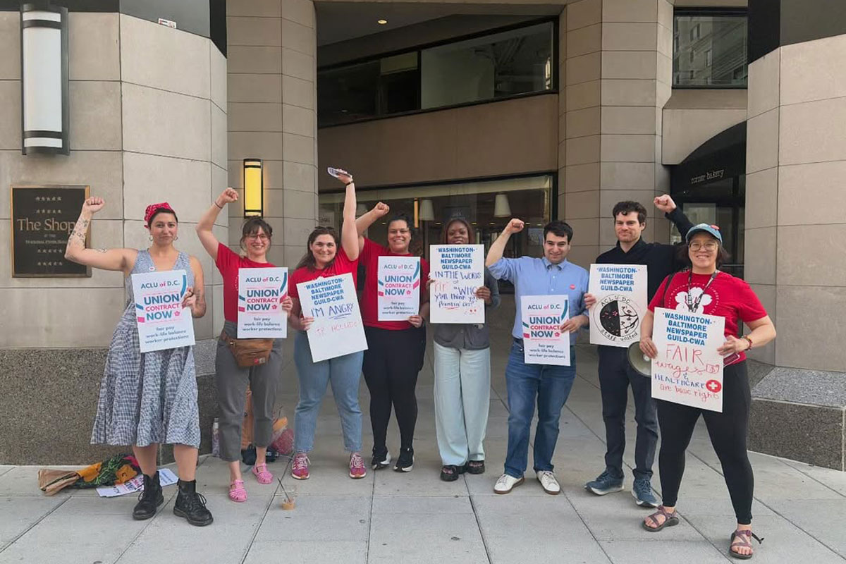 Workers of ACLU DC pose for a photo with signs supporting their union.