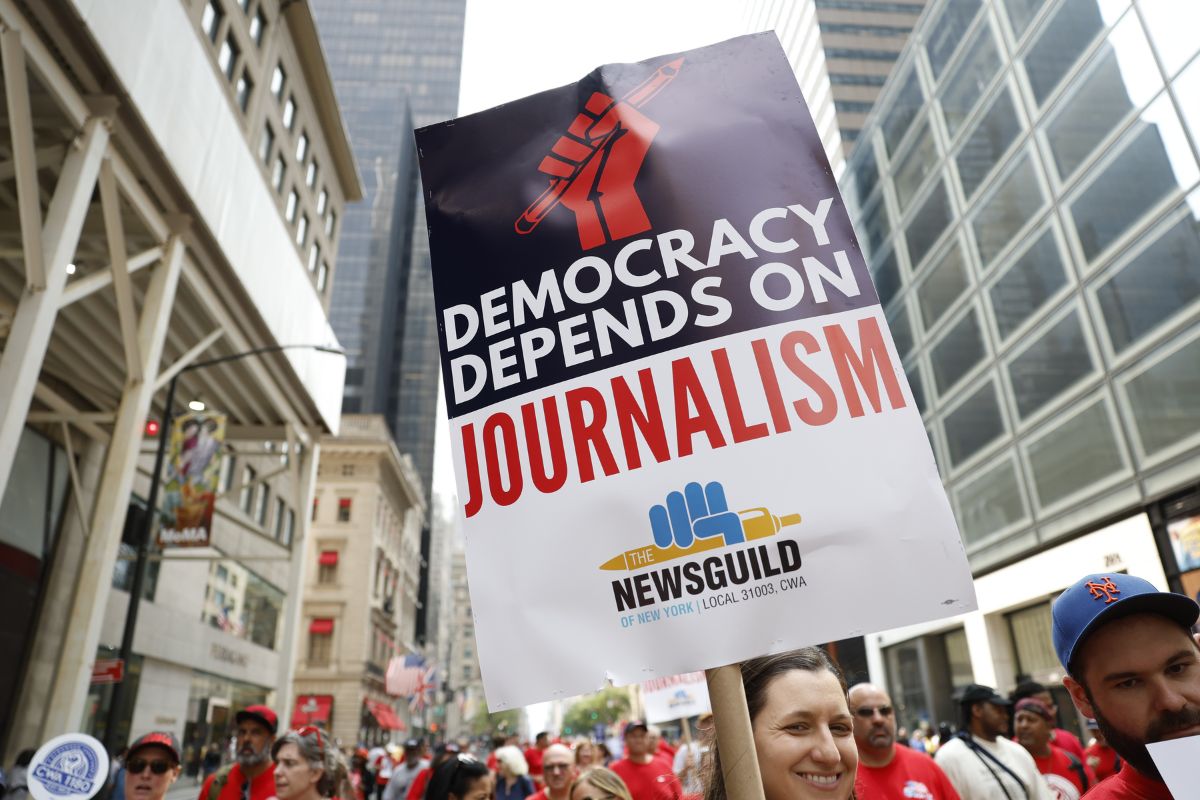 Photo of members of The NewsGuild of New York marching in the New York City Labor Day Parade with a sign reading "Democracy Depends on Journalism"